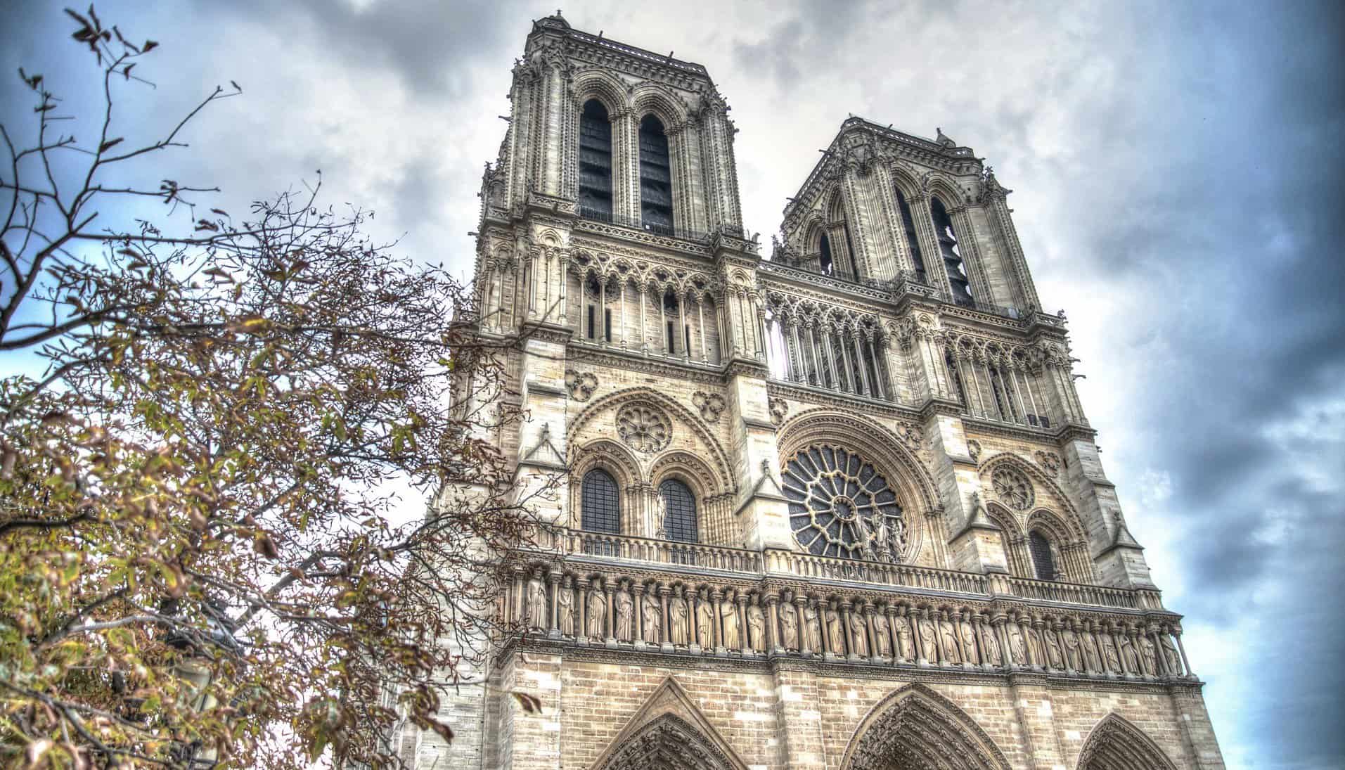 Towers of Notre Dame are seen from below at street level.