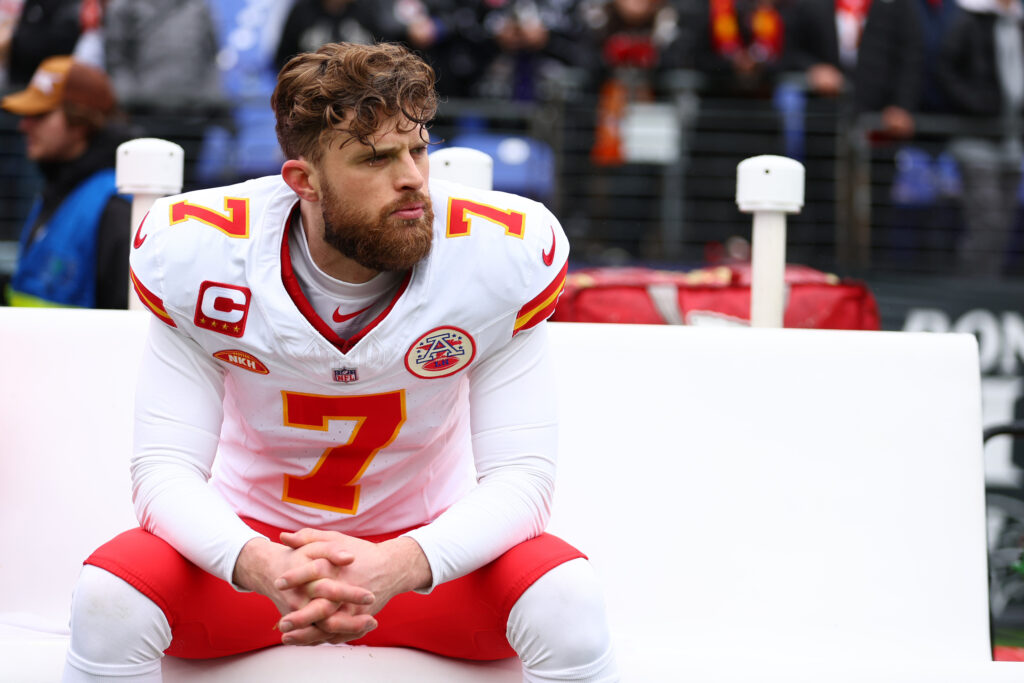 Harrison Butker sits on the sidelines of a football field.