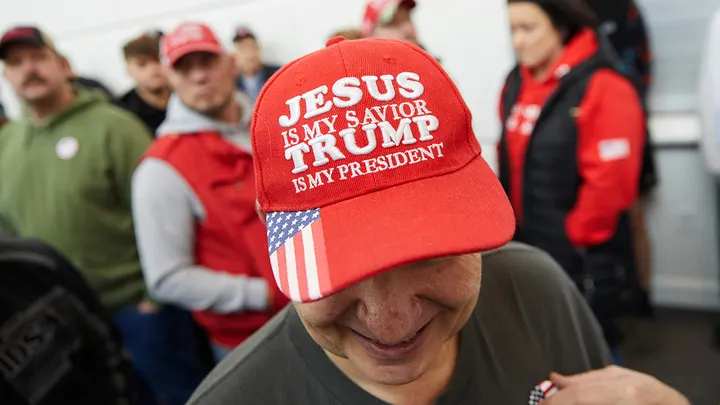 Person wearing a red hat saying "Jesus is my Savior Trump is my President".