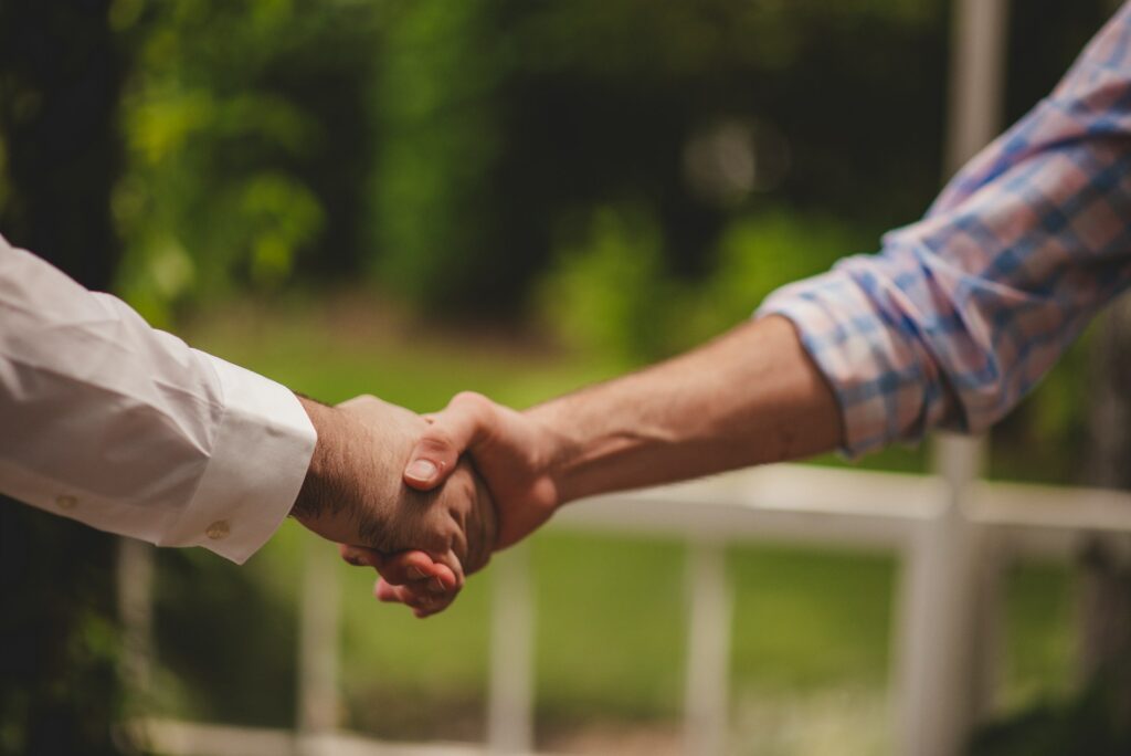 Two men shaking hands, one in professional attire.