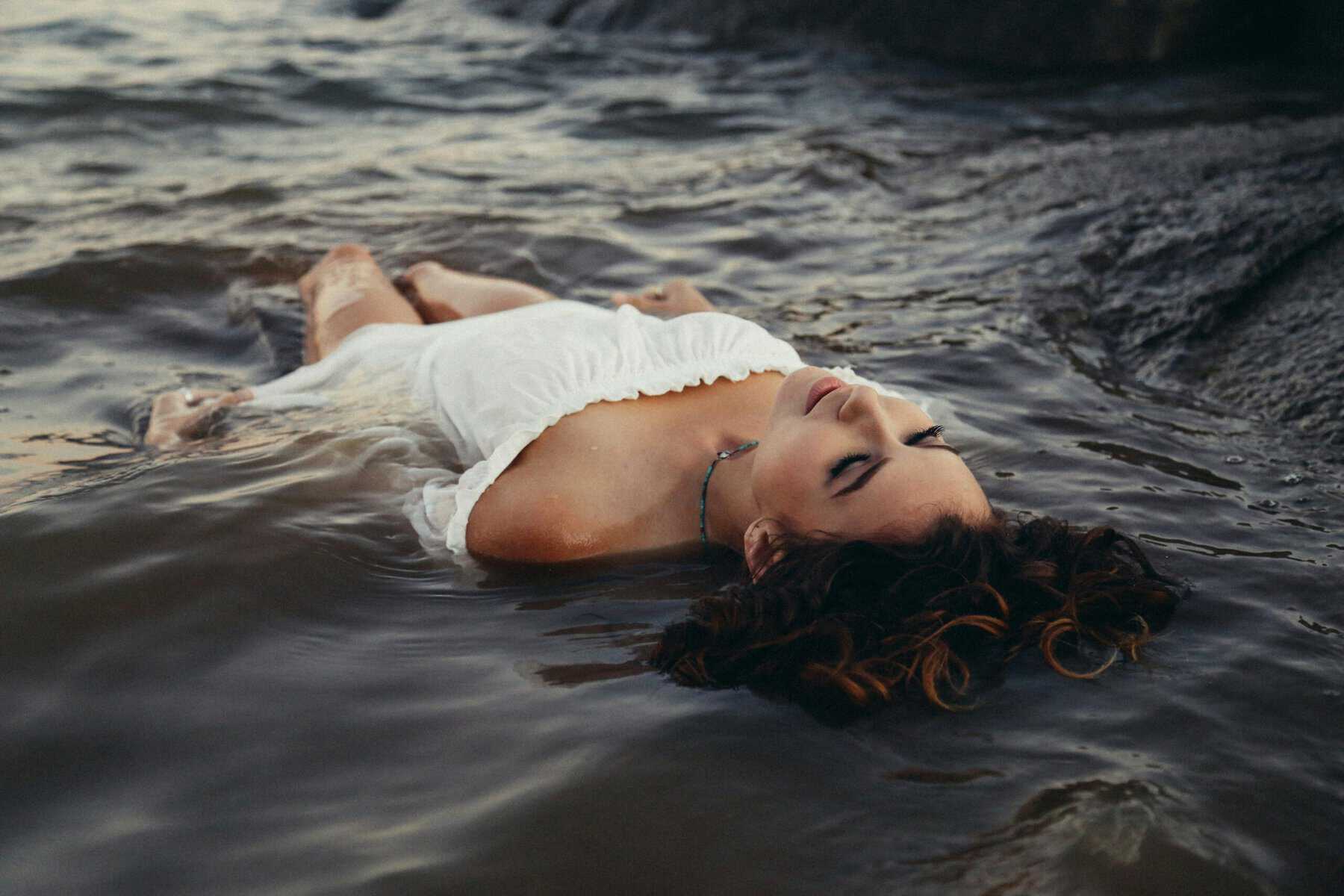 Young woman laying on her back on water.