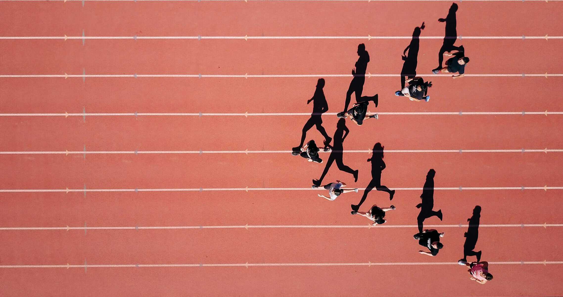 Runners and their shadows on a track.