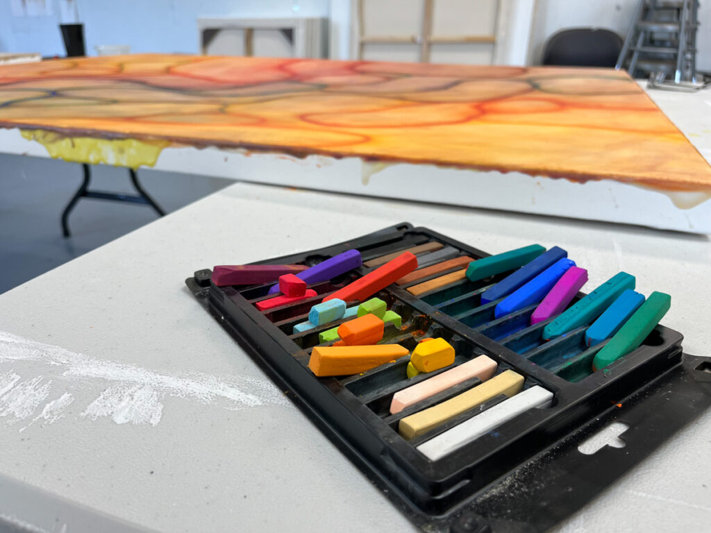 Chalk pastels with a paining and art studio in the background.