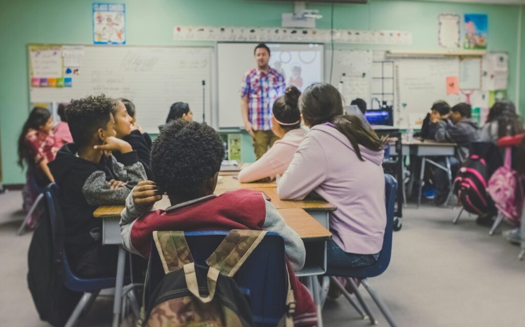 A teacher teaching at the front of a classroom.