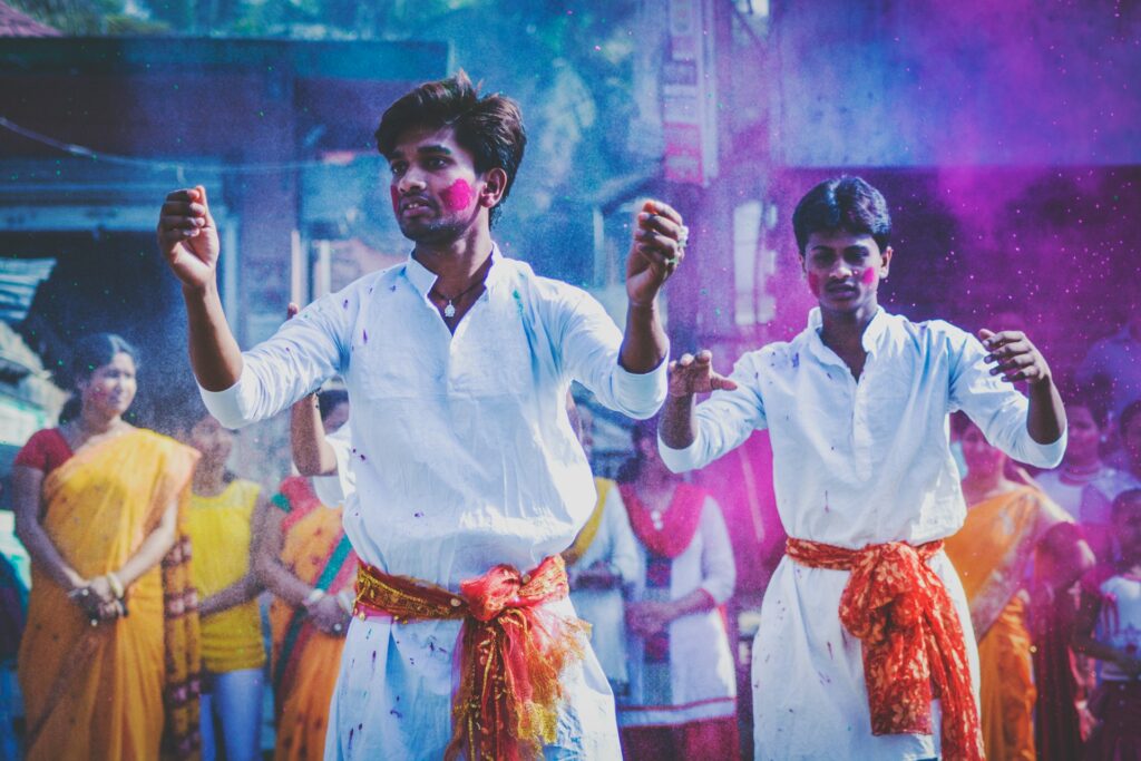 Two men seemingly dancing at a Holi festival.