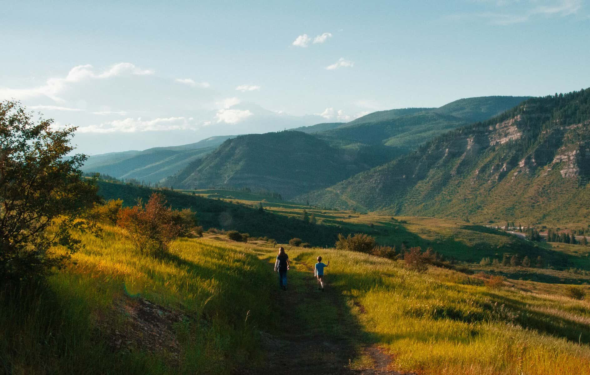 Two people walking surrounded by low mountains.