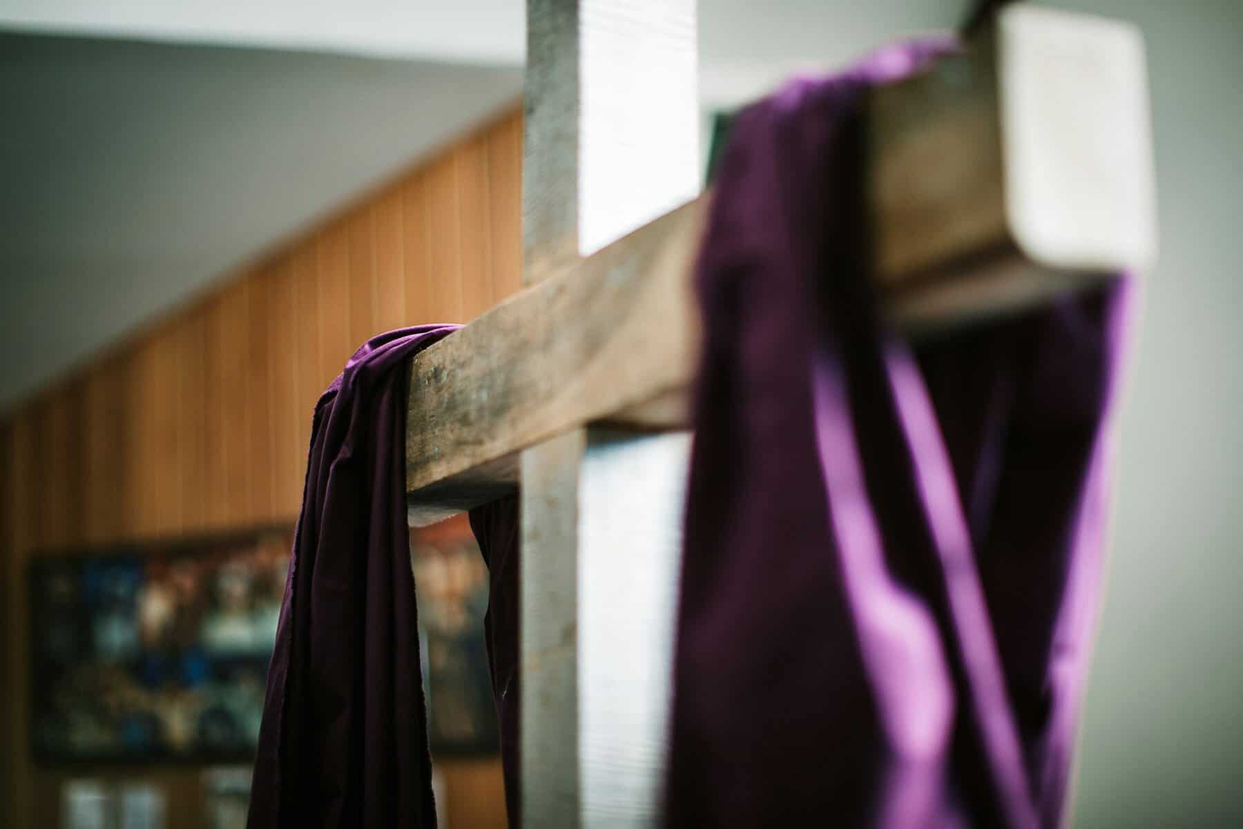 A wooden cross draped with a purple fabric and in a forced perspective.