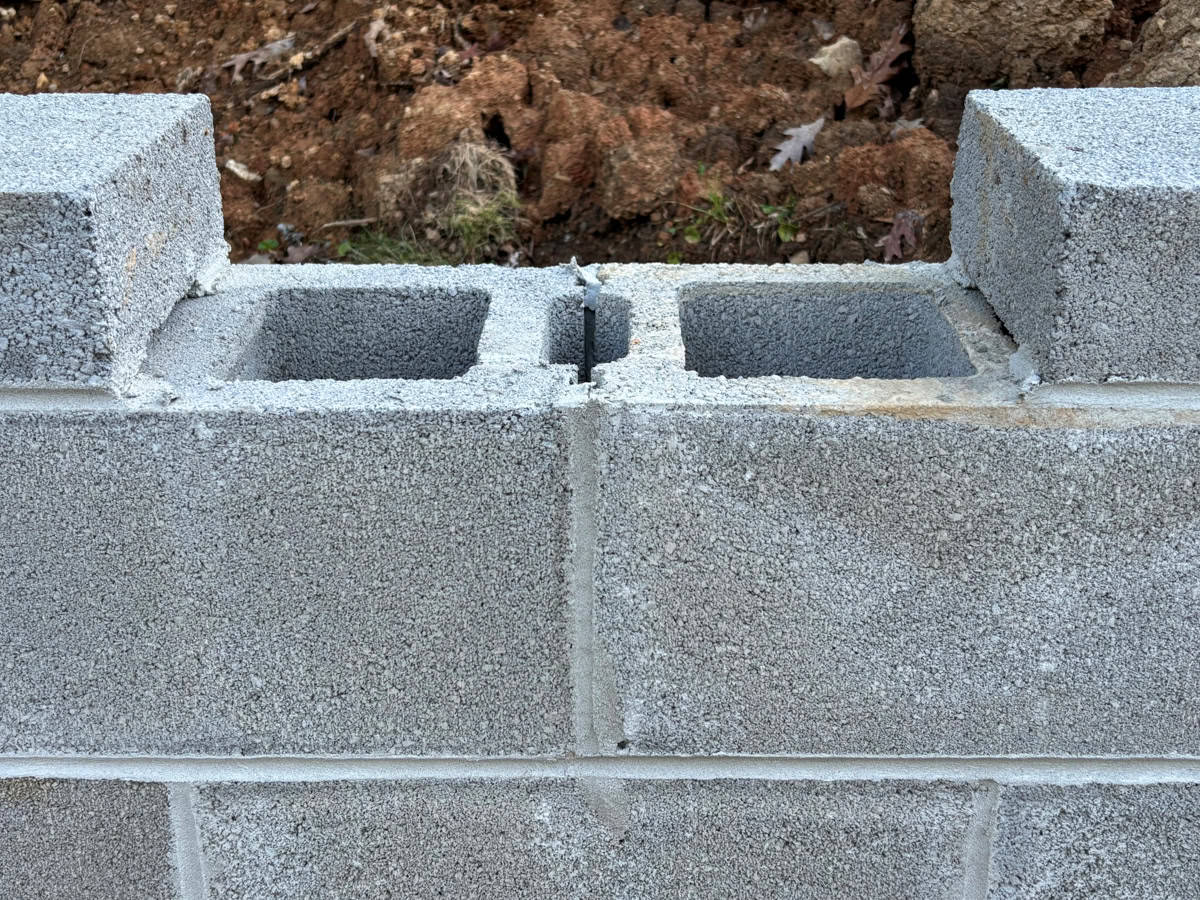 Grey cinder block wall with a cap stone not yet set.