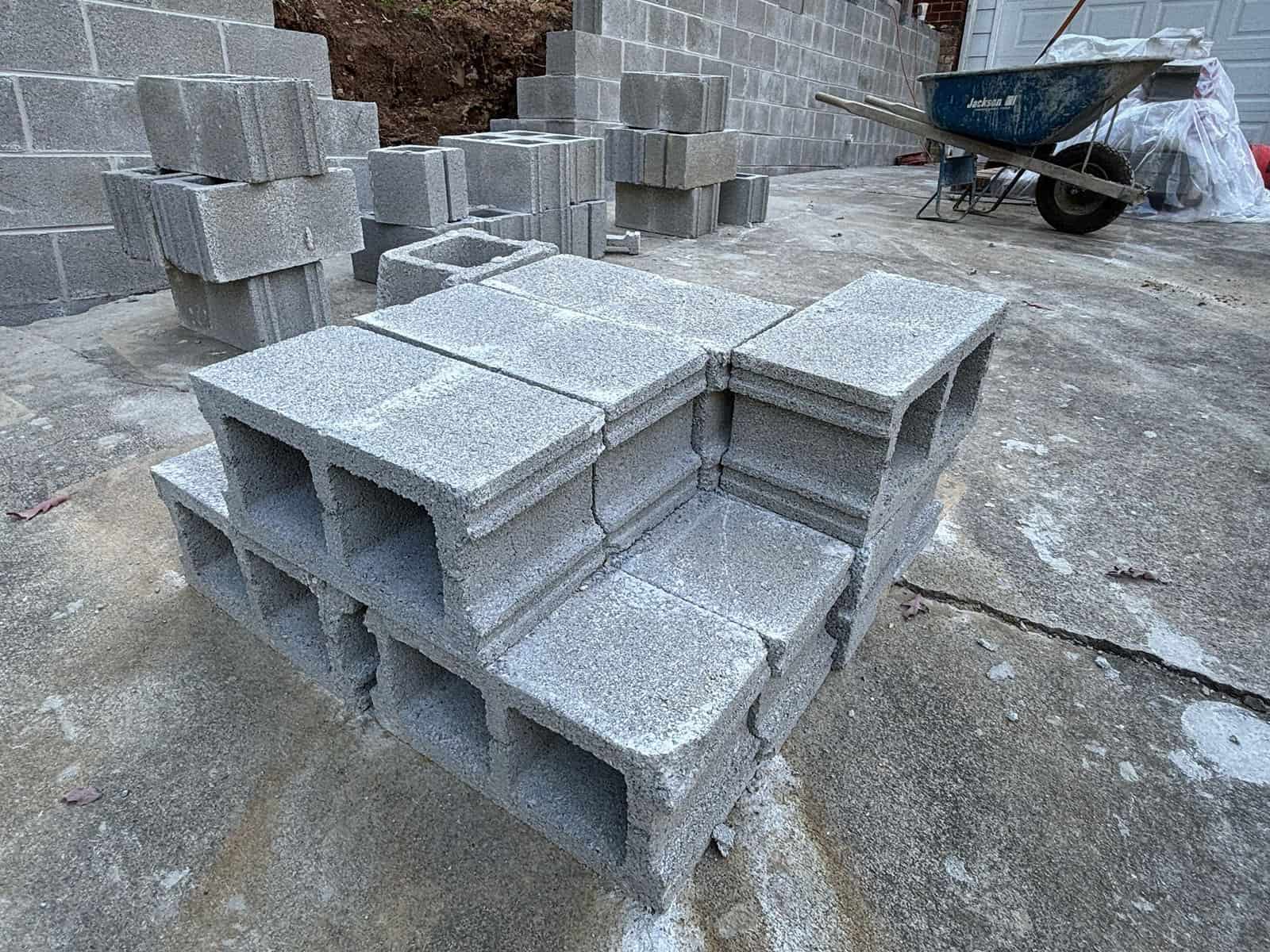 grey cinderblocks stacked in front of a partially completed wall.