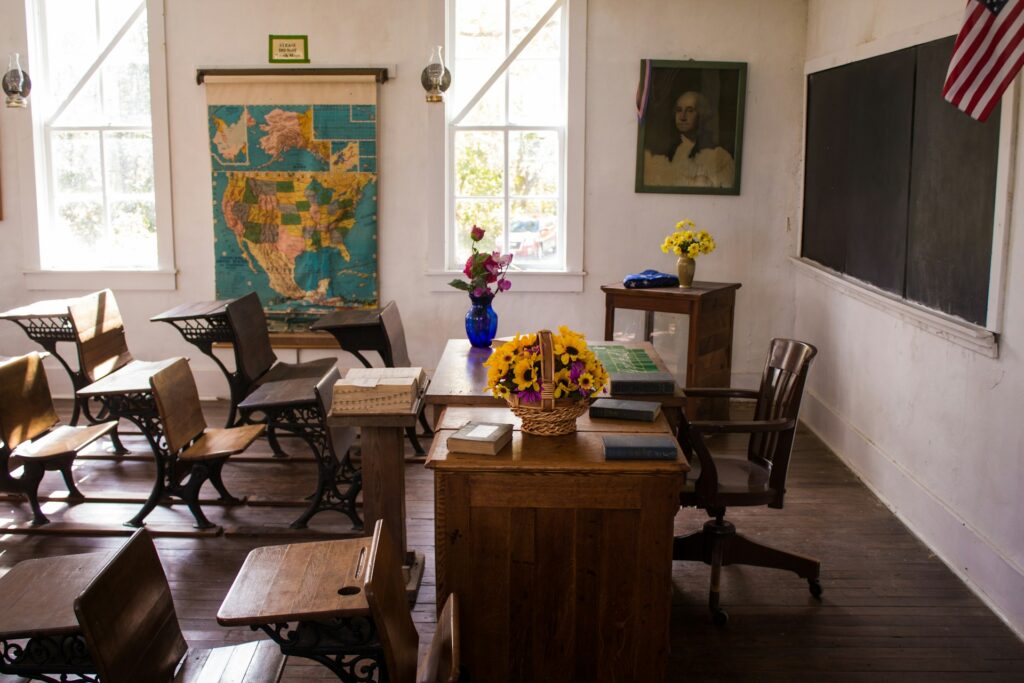 A historic classroom as seen from the side with student and a teacher's desk.