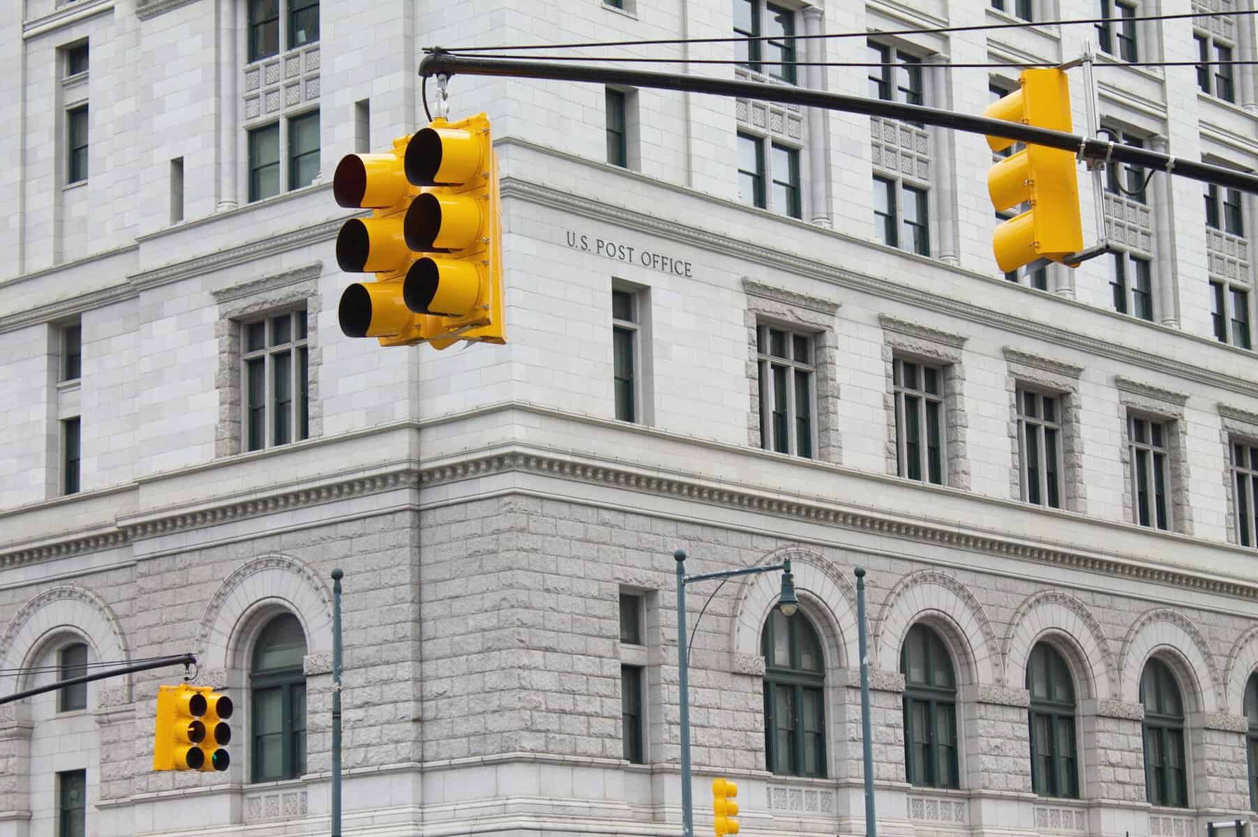 A stone U.S. Post Office building as seen from a street corner.