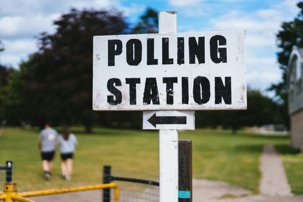 A white sign with black lettering that says "Polling Place" with a directional arrow.