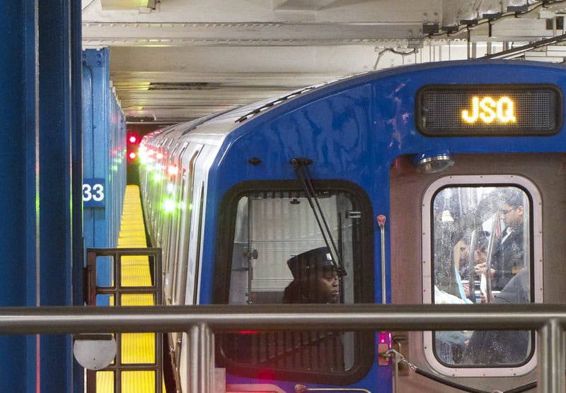 The front of a PATH train is seen close up in a station with the driver visible.