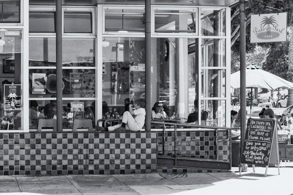 A young boy sits on a wall outside Delores Park Cafe in San Francisco.