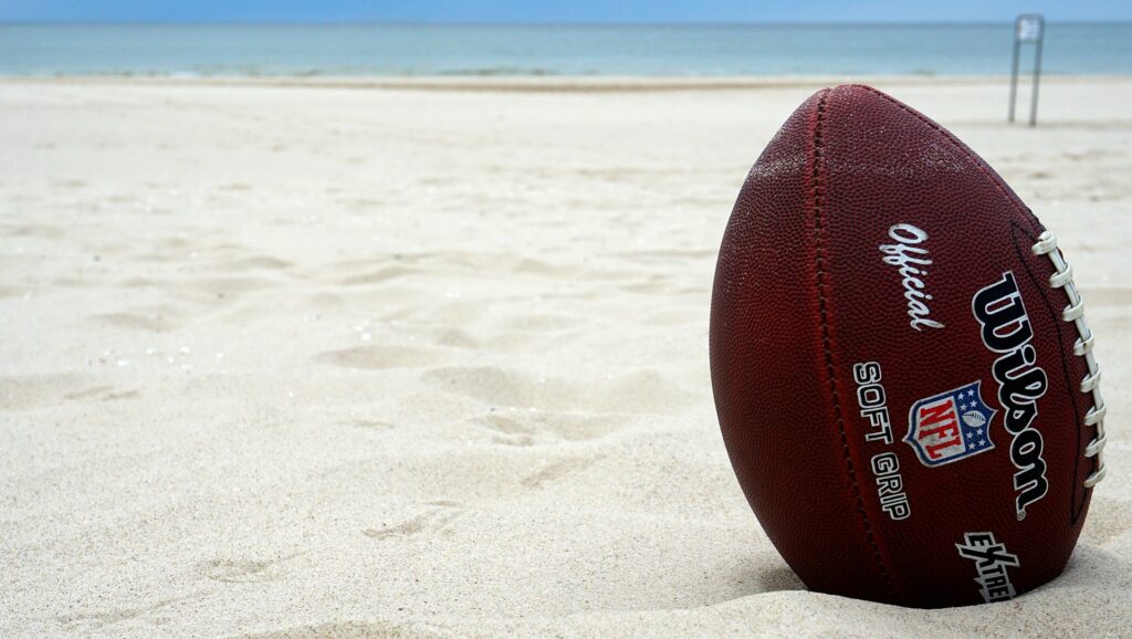 A football stuck in white beach sand.