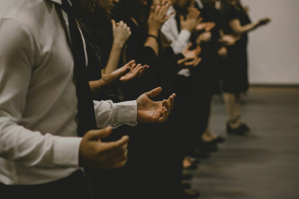 Faceless people in a line with hands raised as if in worship.