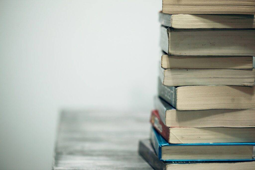 paperbacked books stacked on a table with spines not visible.