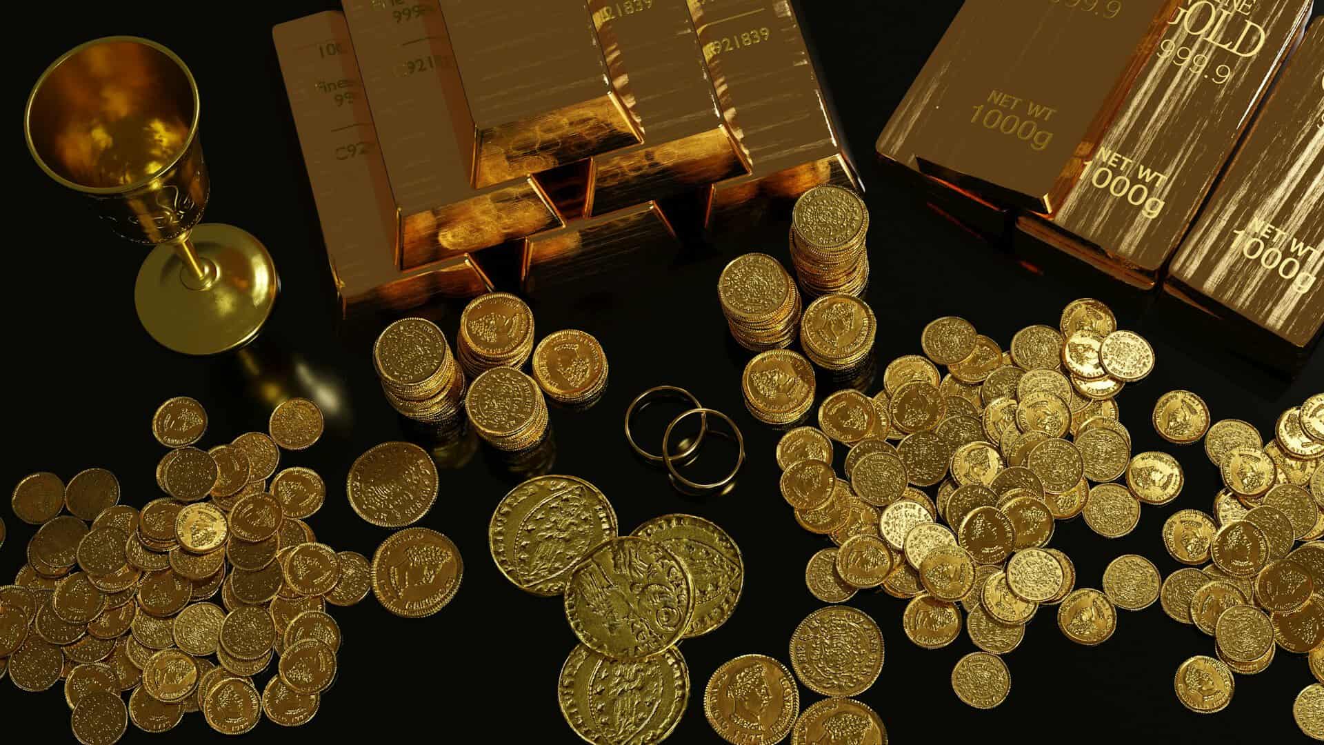 Gold coins, bars, rings and a chalice sit on a table top.