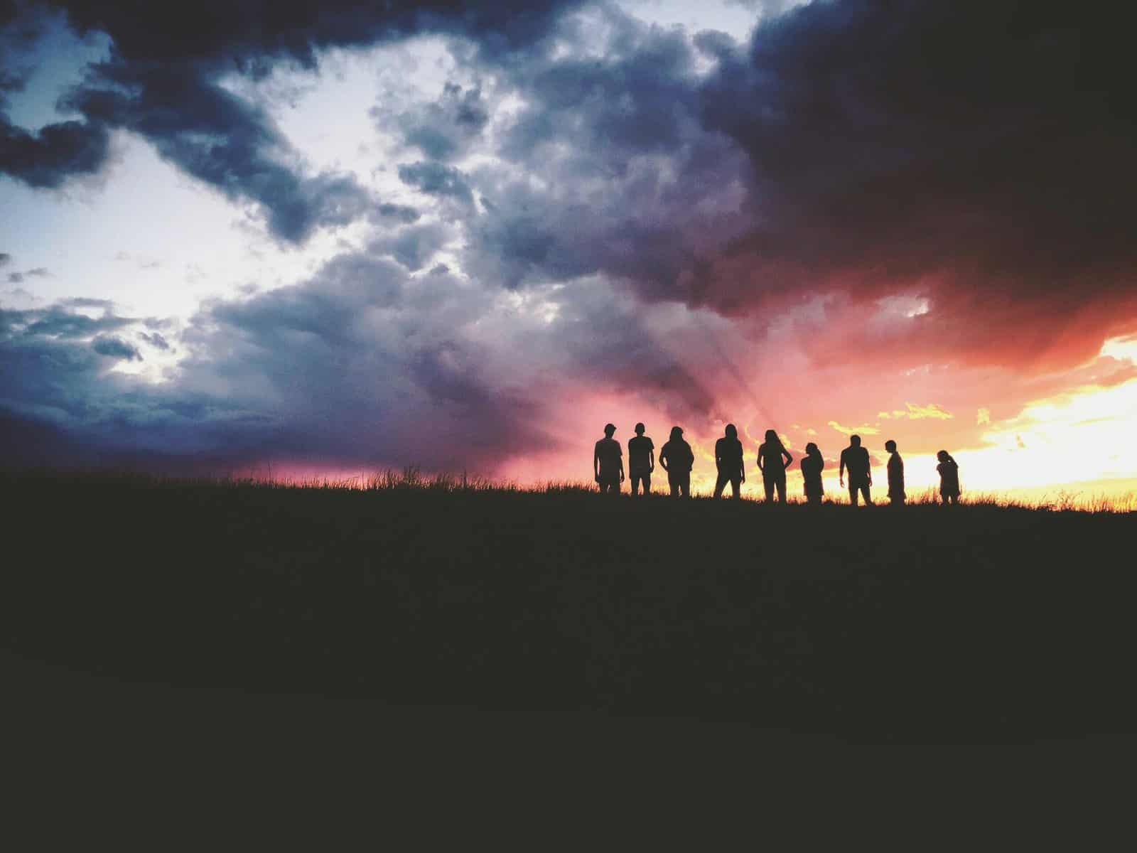 nine people silhouetted in the distance against a sunset.