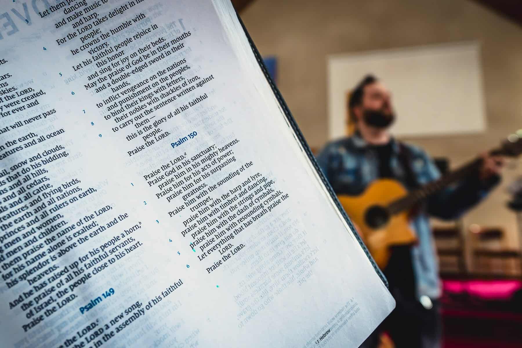 Bible close up with a guitarist in the background.