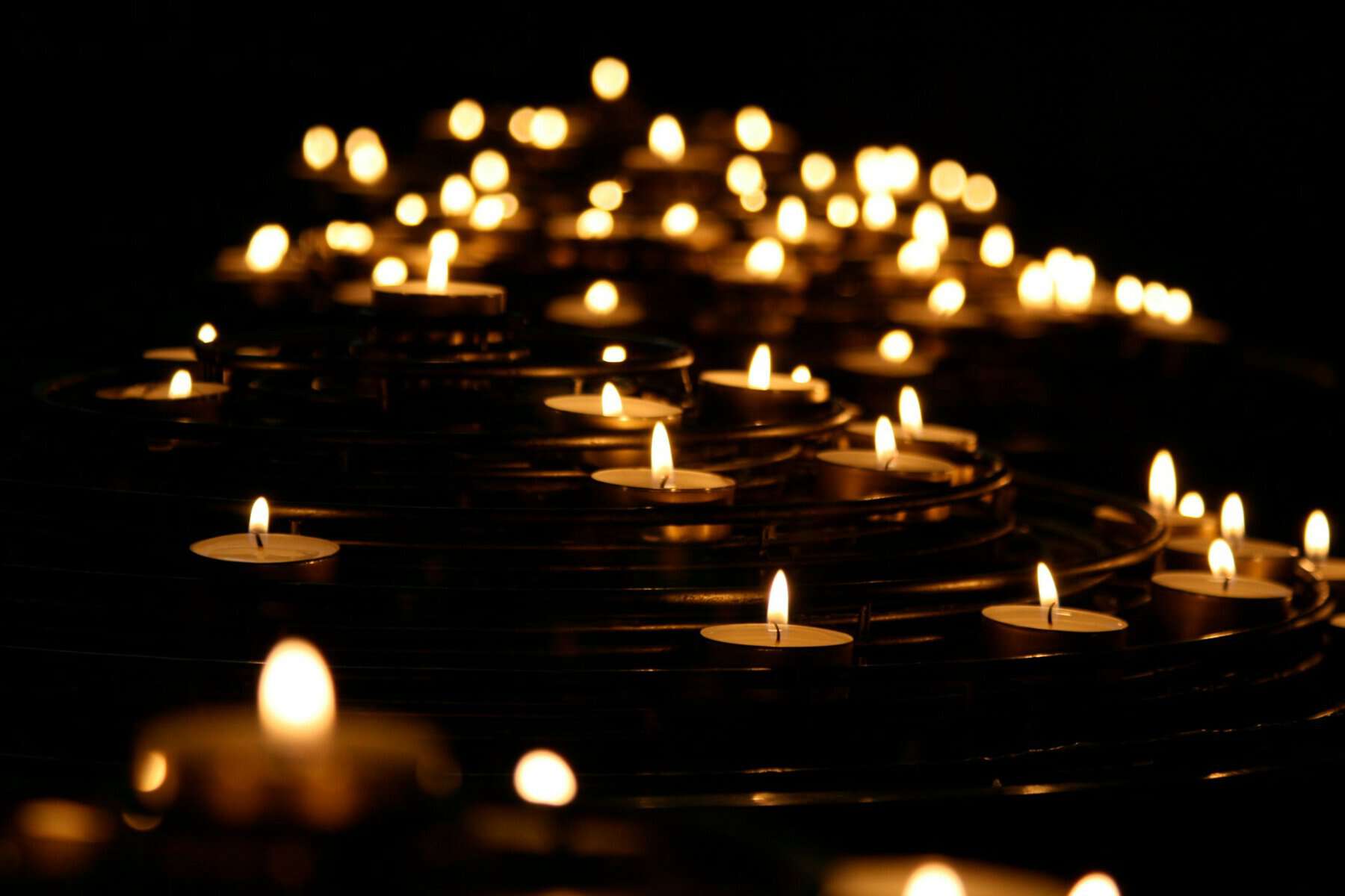 Many lit candles in low light.