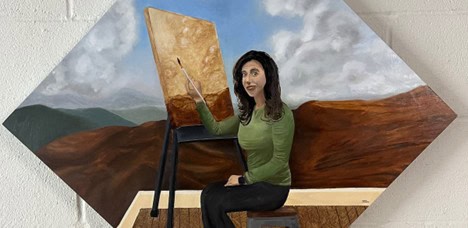 The artist paints herself seated and painting at an easel.