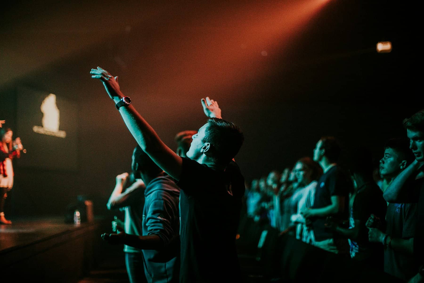 Man raising arms in low light worship.