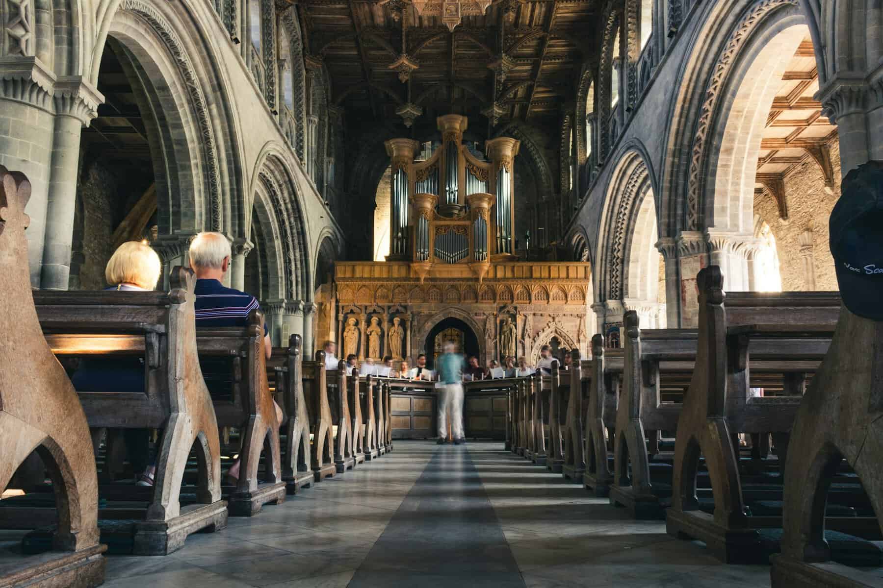 People sitting on a pew in a large stone church.