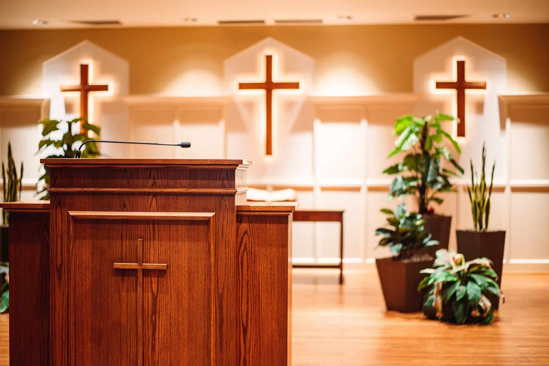 The pulpit of a church and behind it are shown with three crosses hanging.