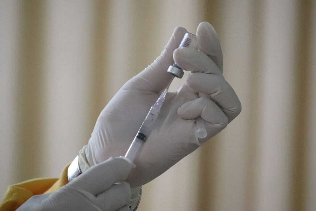 Hands holding a vaccine vial and syringe.