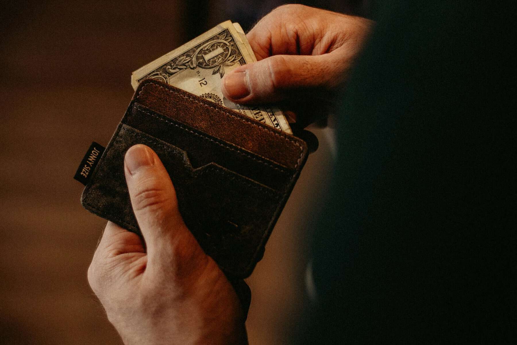 A man getting dollar bills from a wallet.