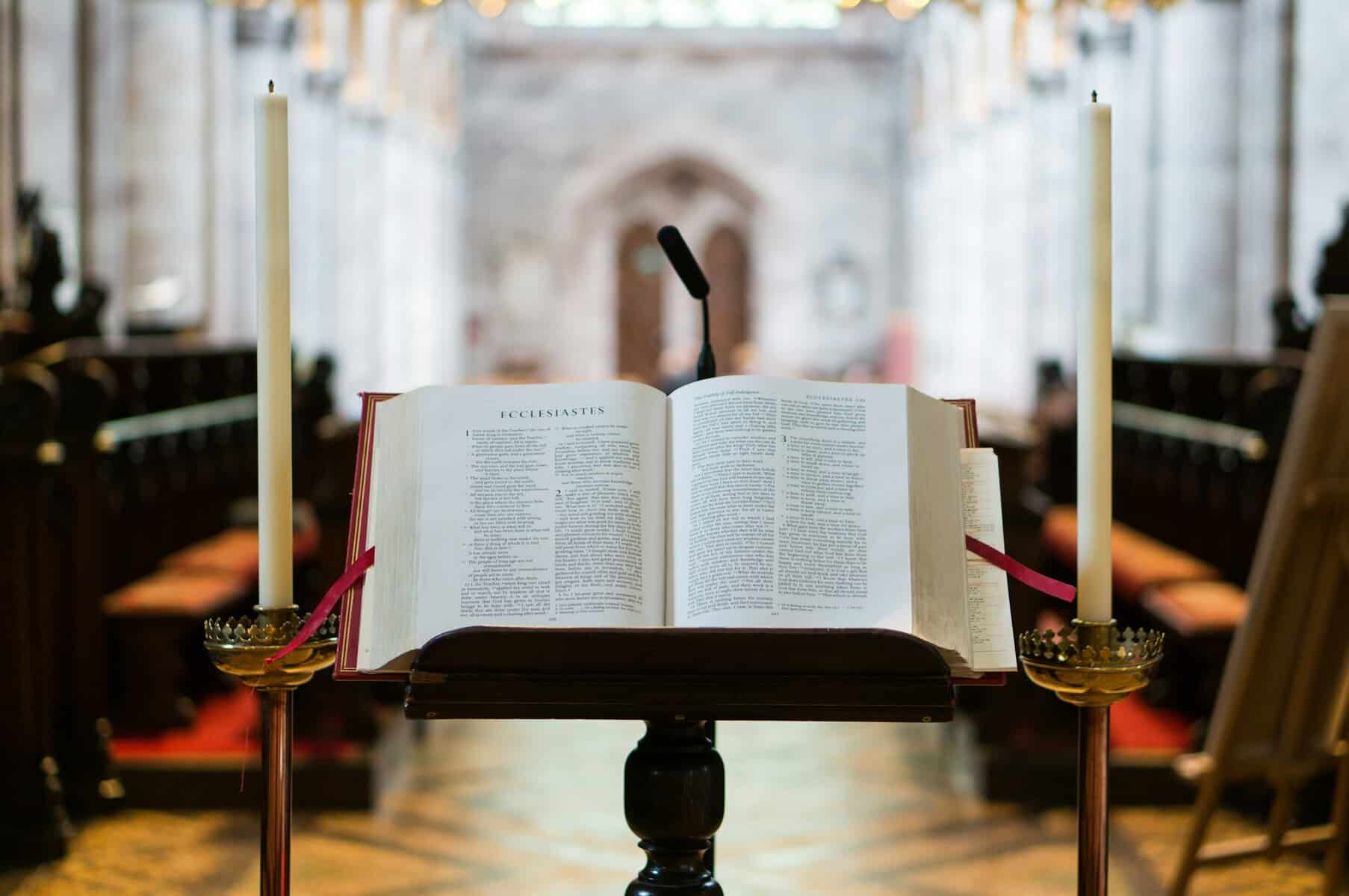 An open bible on a stand with a cathedral behind it.