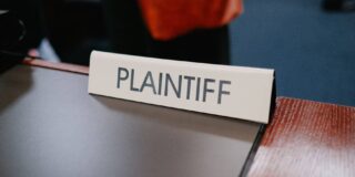 A sign on a desk says "plaintiff."