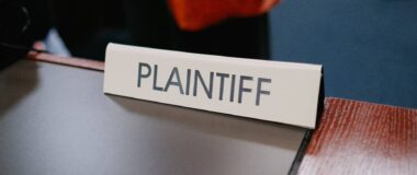 A sign on a desk says "plaintiff."