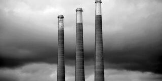 Three smokestacks in grey scale.