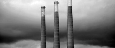 Three smokestacks in grey scale.