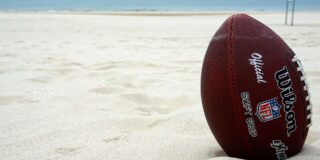 A football stuck in white beach sand.