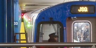 The front of a PATH train is seen close up in a station with the driver visible.