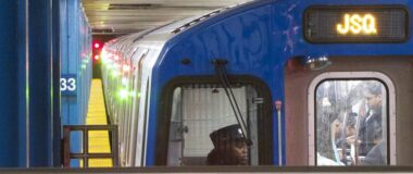 The front of a PATH train is seen close up in a station with the driver visible.