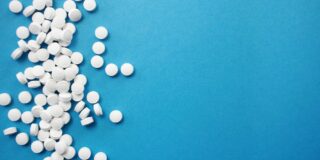 A group of round white pills in a line on the left of a blue background.