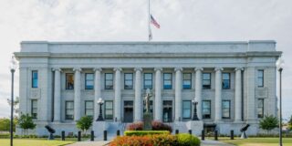 A courthouse with the U.S. flag half staff.