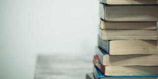 paperbacked books stacked on a table with spines not visible.