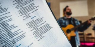 Bible close up with a guitarist in the background.