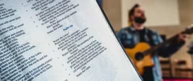 Bible close up with a guitarist in the background.