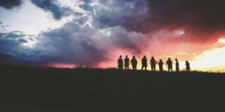 nine people silhouetted in the distance against a sunset.