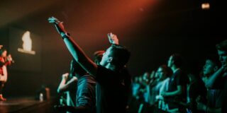 Man raising arms in low light worship.