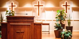 The pulpit of a church and behind it are shown with three crosses hanging.