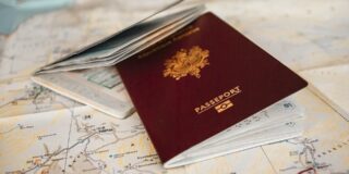 A burgundy passport is shown laying on a map.