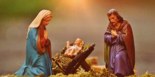 Figurines of Mary, Joseph and baby Jesus are shown in soft light.