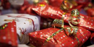 Small gifts wrapped in red and gold paper sit in a pile.